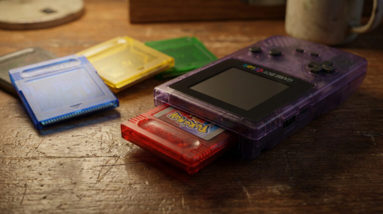 Une console Game Boy Color violette avec une cartouche Pokémon rouge, entourée d'autres cartouches de jeux colorées.