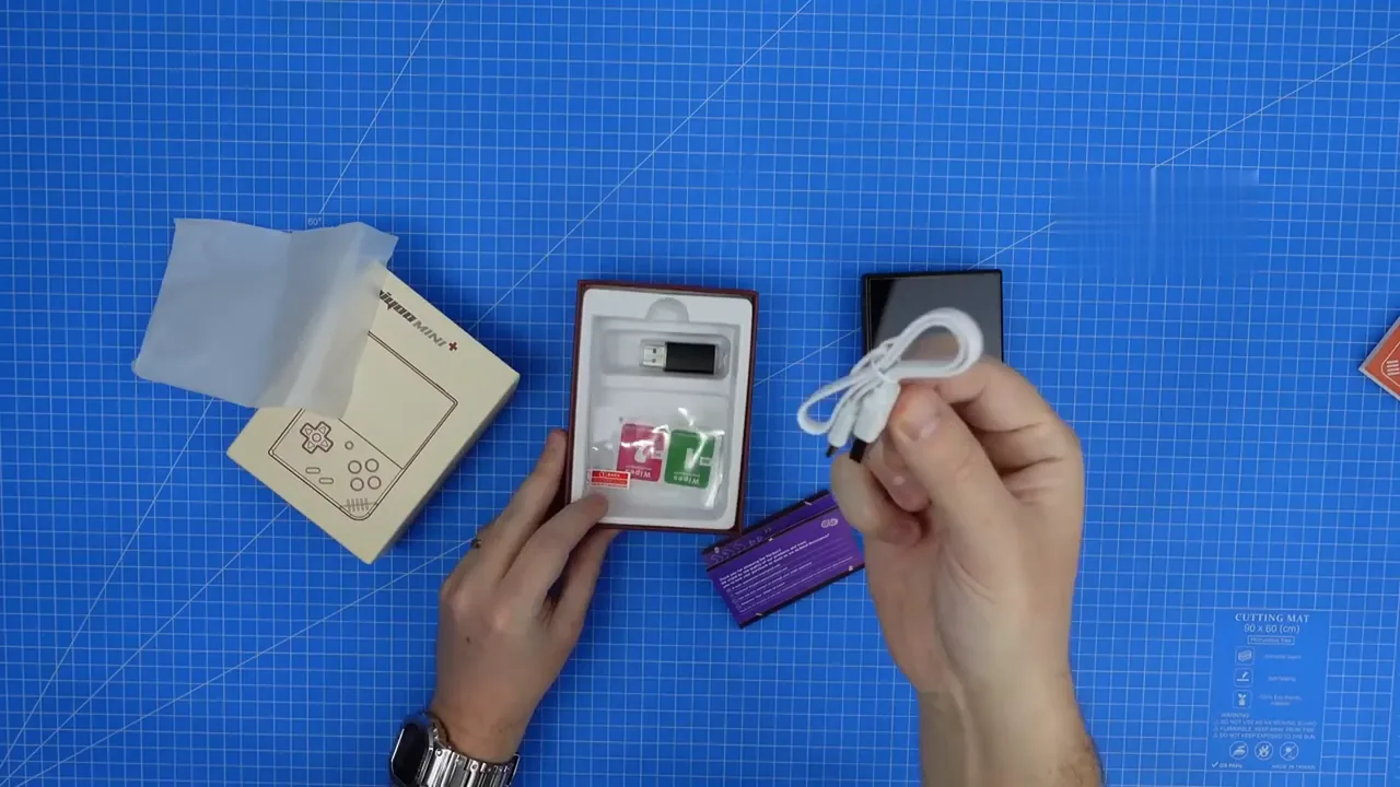 Miyoo Mini Plus posée à côté de sa carte micro-SD, du câble et du film de protection
