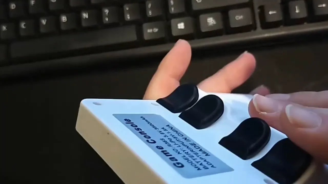 Doigts posés sur les gâchettes L et R d'une R36S blanche, point faible ergonomique de la console