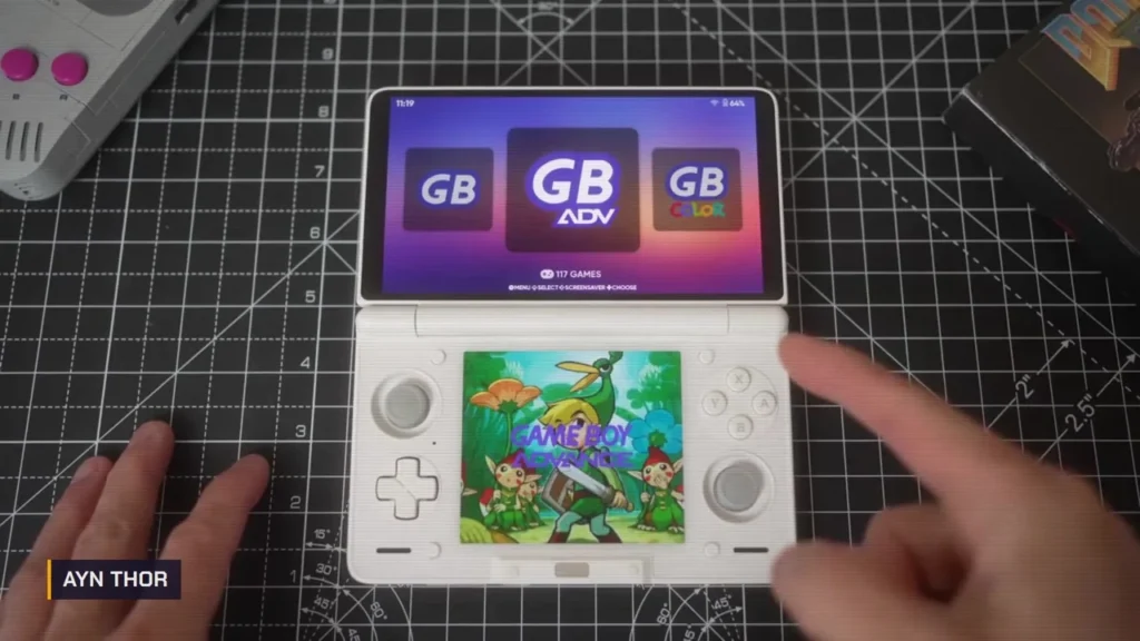 AYN Thor blanche ouverte sur un tapis de découpe, menu Game Boy Advance en haut et écran du bas presque carré